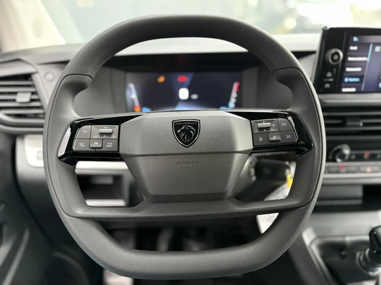 Vue rapprochée du volant noir du Peugeot Expert Fourgon 2025 avec commandes intégrées et logo lion central.