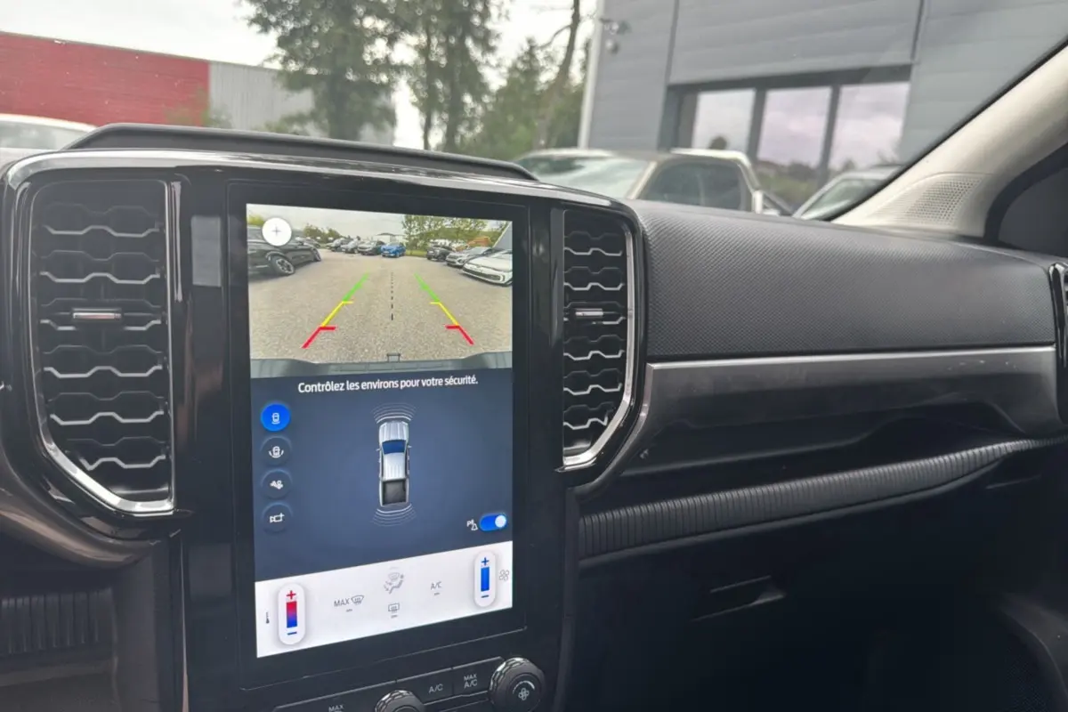 Vue intérieure du tableau de bord du Ford Ranger 2025 avec écran tactile affichant la caméra de recul et les commandes climatisation.