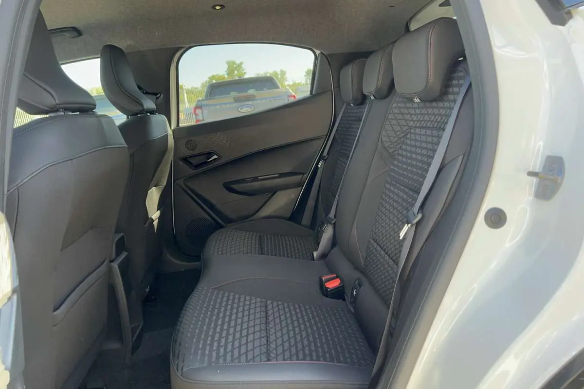 Vue intérieure côté droit sur la banquette arrière noire au tissu texturé d'une Renault Clio blanc glacier 2026.
