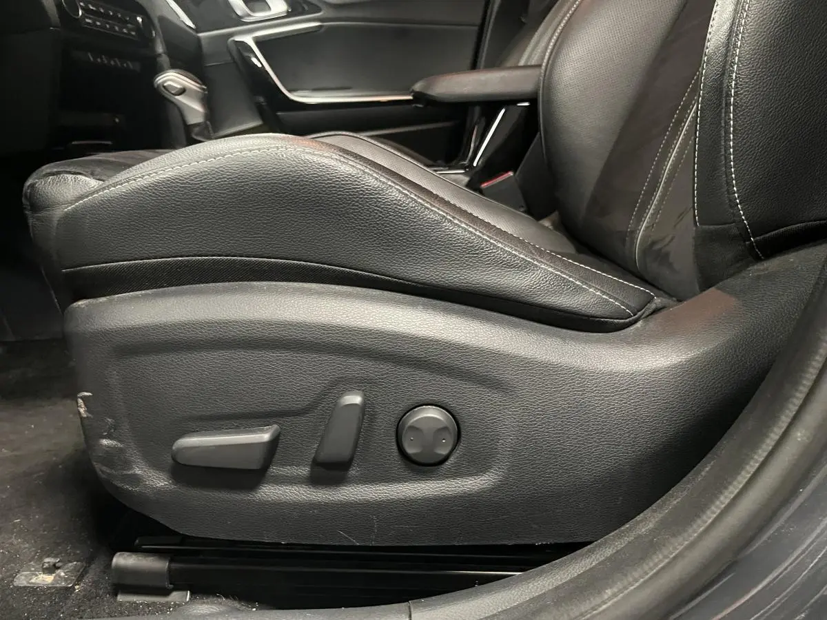 Gros plan sur le siège conducteur en cuir noir avec commandes électriques dans l'habitacle d'une Kia Ceed 2023.