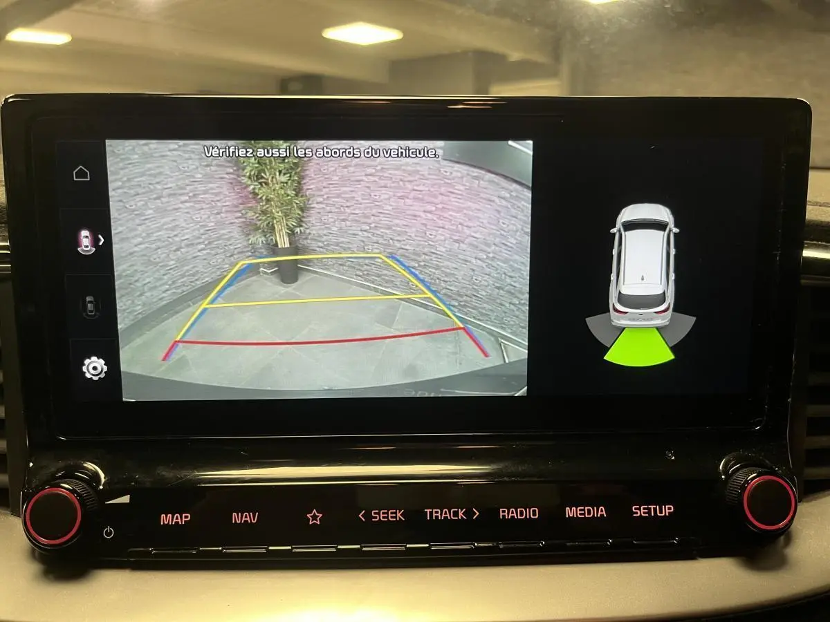 Écran tactile intérieur montrant la caméra de recul et l'aide au stationnement du Kia Ceed gris 2023.