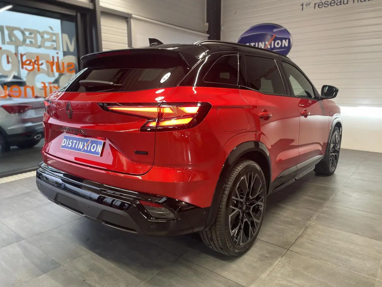 Vue 3/4 arrière droite du Renault Austral rouge métallisé avec toit noir et jantes alliage noires.