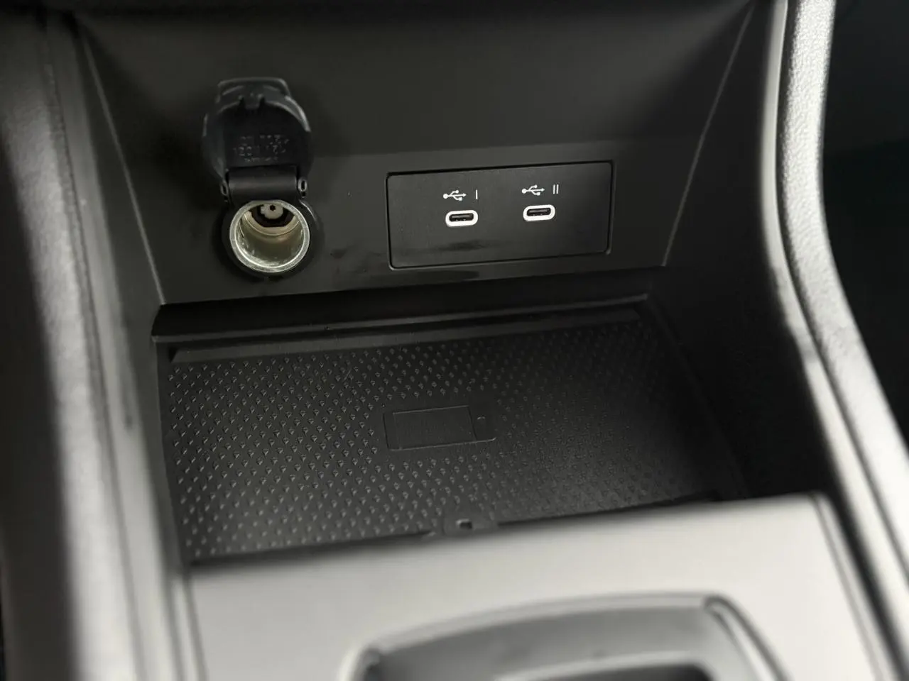Gros plan sur la console centrale du Renault Captur 2025, montrant prises USB-C, prise 12V et chargeur induction noir.