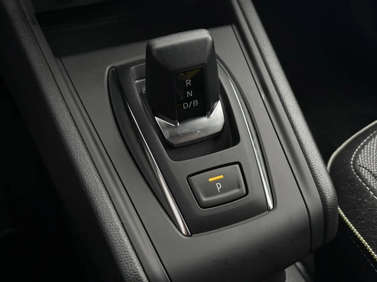 Gros plan sur la commande de boîte automatique et bouton parking du Renault Captur 2025, intérieur noir et coutures contrastées.