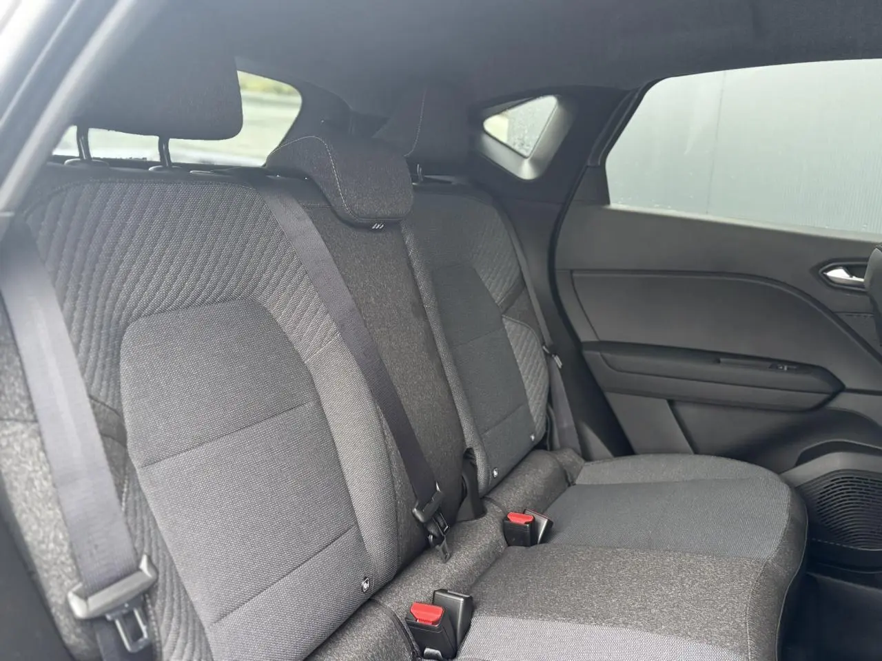Vue intérieure arrière droite des sièges arrière gris foncé du Renault Captur 2025, avec ceinture de sécurité et appuie-tête.