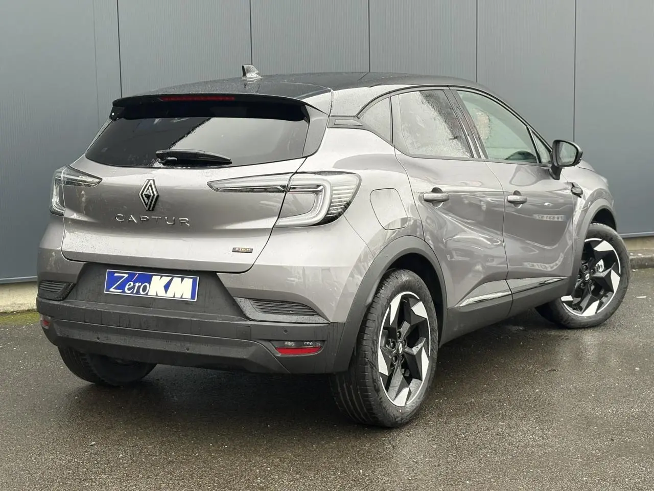 Vue 3/4 arrière droite du Renault Captur gris Cassiopée avec toit noir, jantes 18 pouces et caméra de recul visible.