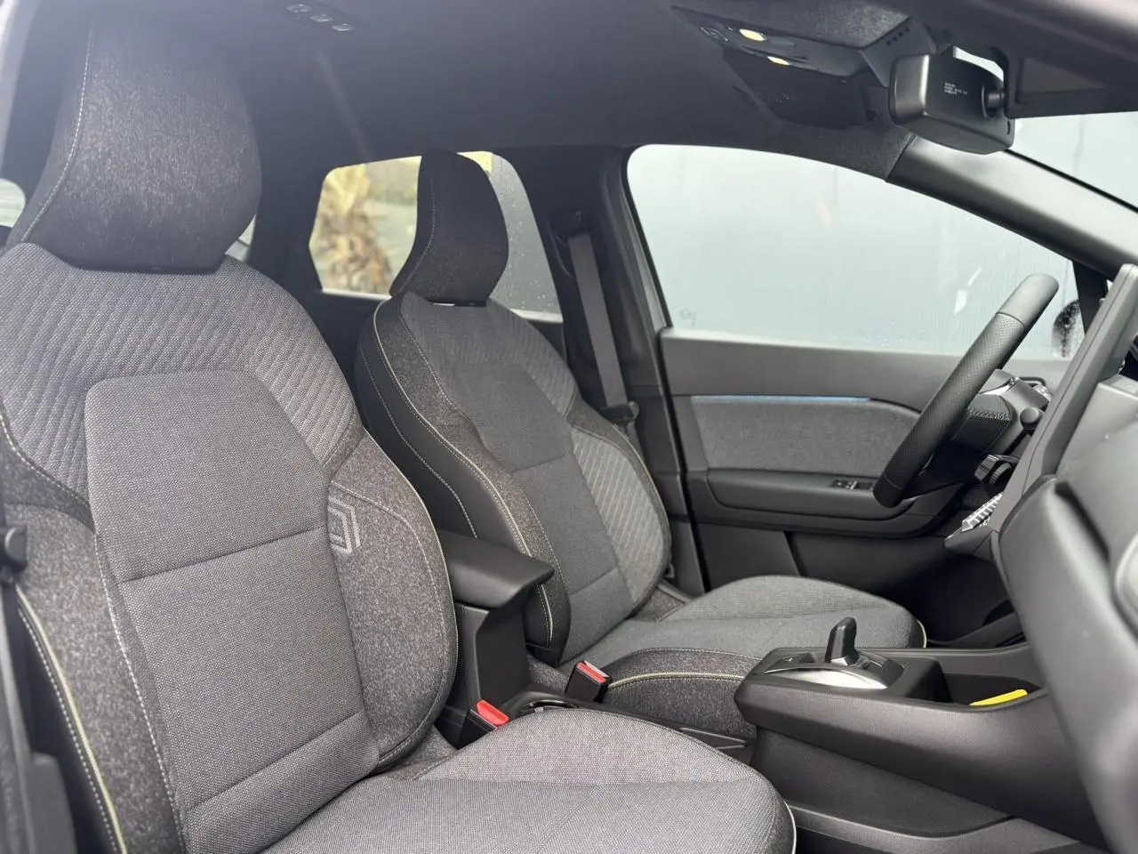 Vue intérieure côté droit du Renault Captur 2025, sièges gris avec console centrale et volant textile.