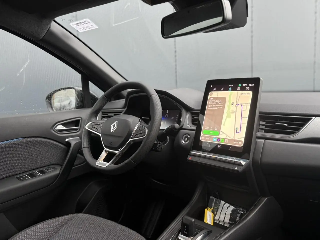 Vue intérieure côté conducteur du Renault Captur 2025, avec tableau de bord numérique et écran tactile vertical central.