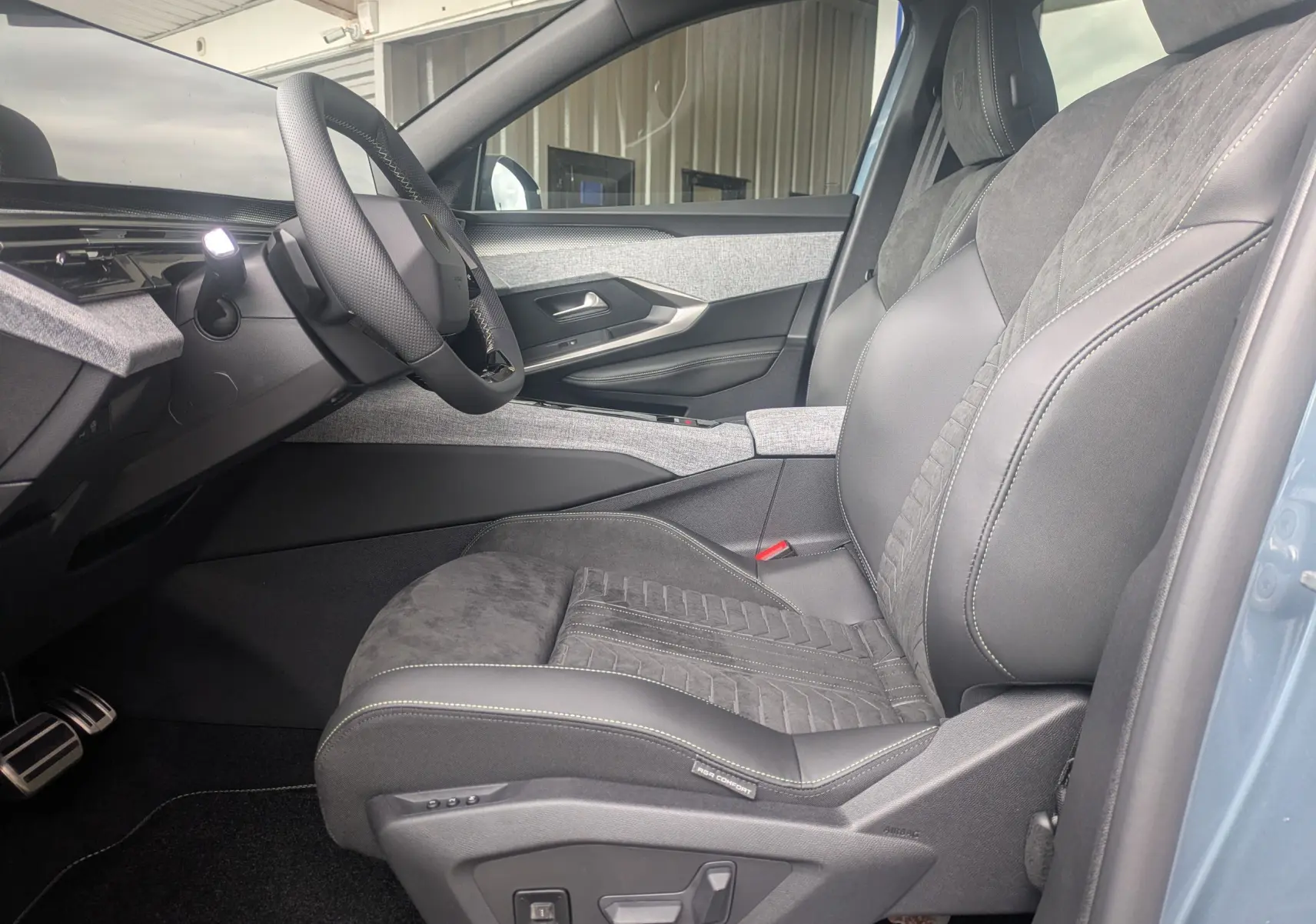 Vue intérieure côté conducteur du Peugeot 3008 Hybrid 145 GT Exclusive 2026, sellerie Alcantara noire et détails gris clair.