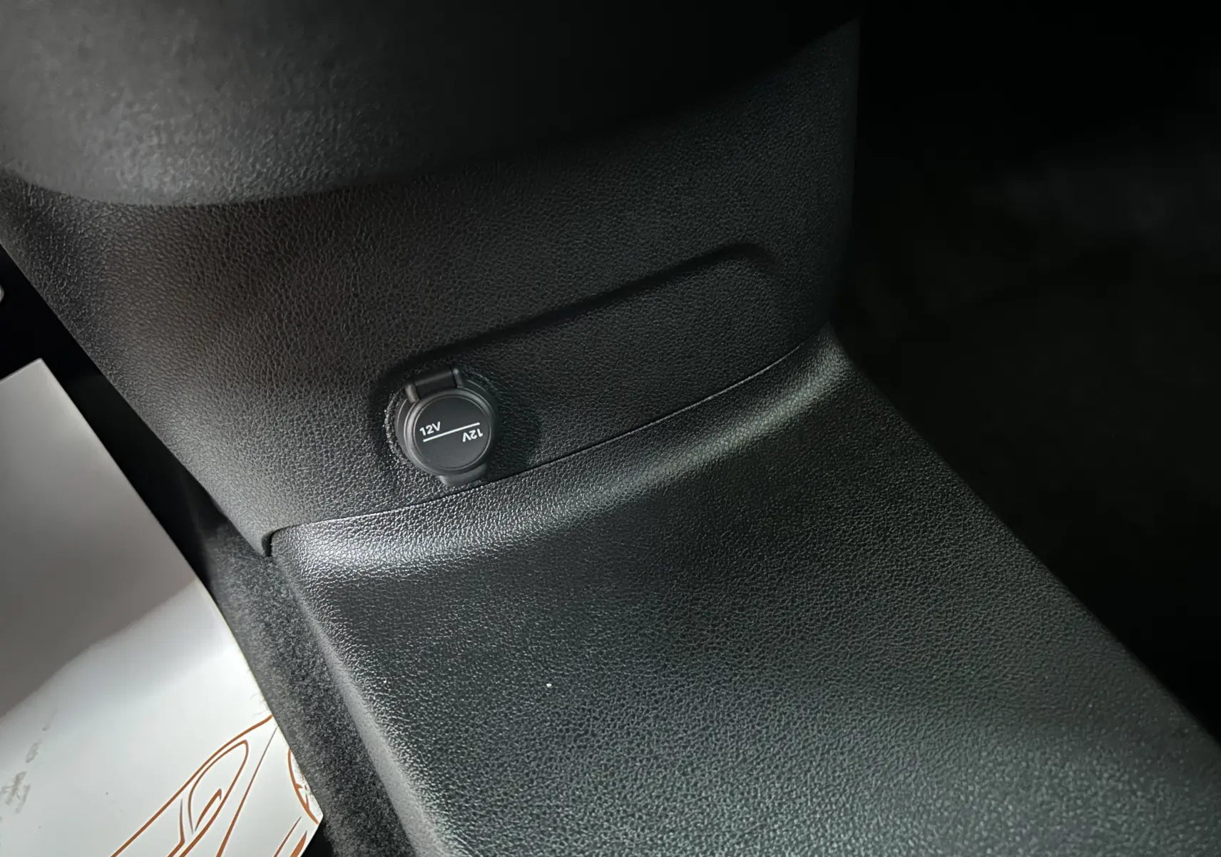 Prise 12V noire sur console centrale en plastique texturé noir du Citroën Berlingo Multispace gris acier.