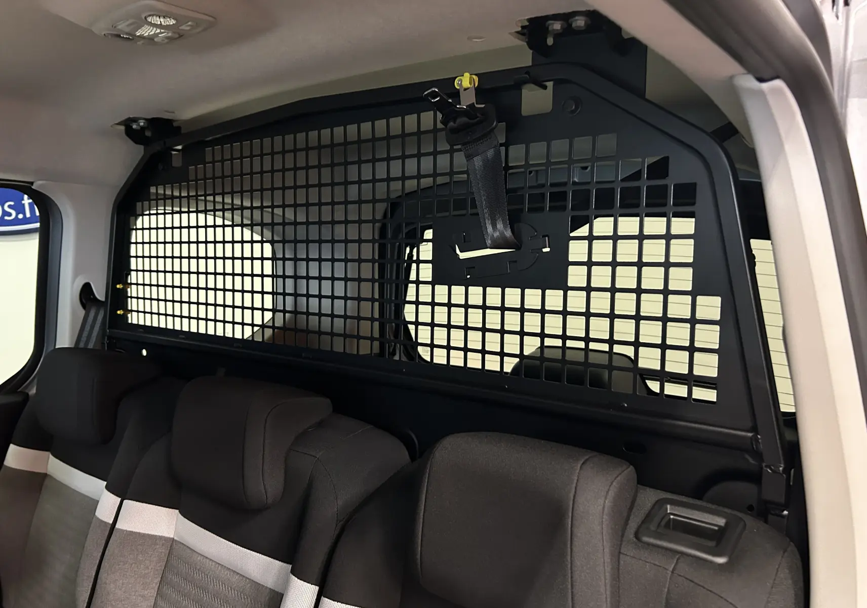 Vue intérieure arrière du Citroën Berlingo Multispace gris acier, montrant la grille de séparation entre sièges et coffre.