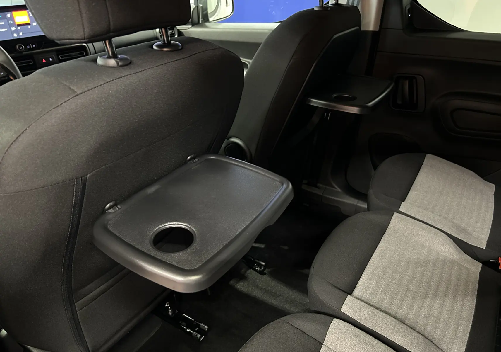 Intérieur arrière du Citroën Berlingo Multispace 2026, sièges tissu bicolore avec tablettes rabattables noires.
