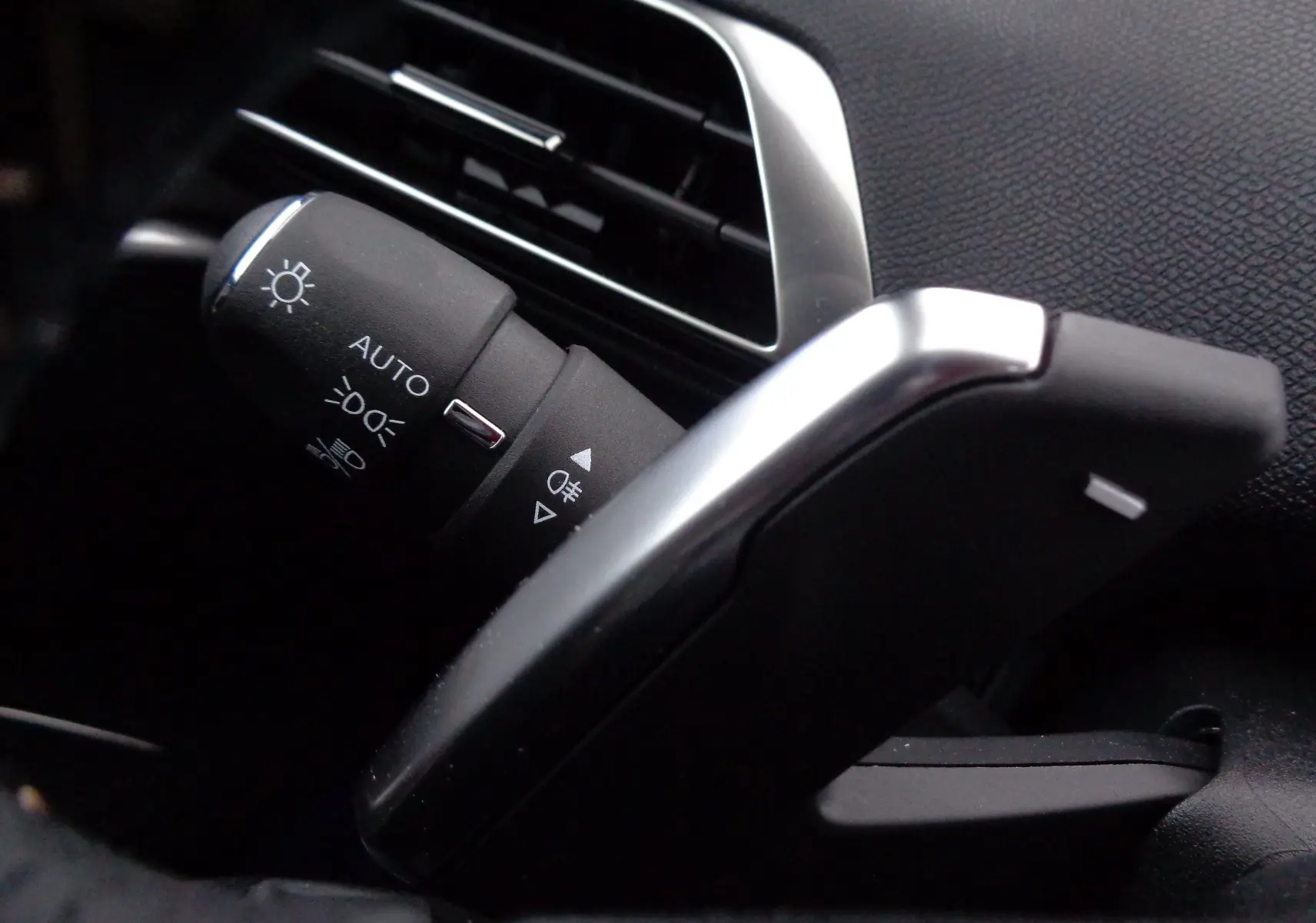 Gros plan sur la commande des feux et la palette de changement de vitesse côté gauche du Peugeot 3008 gris 2023.