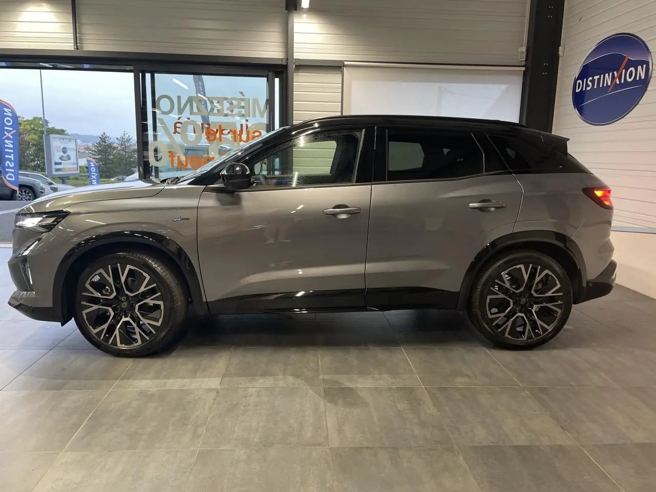 Renault Austral 2025 gris schiste avec toit noir étoilé, vue profil côté gauche en intérieur showroom.