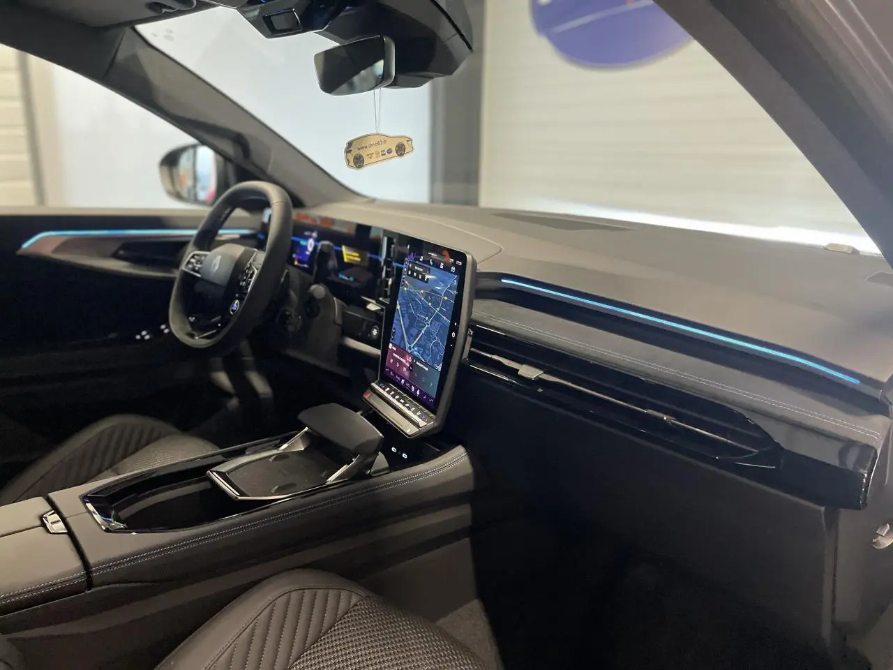 Vue intérieure côté conducteur du Renault Austral 2025 avec écran tactile vertical et ambiance moderne noire.
