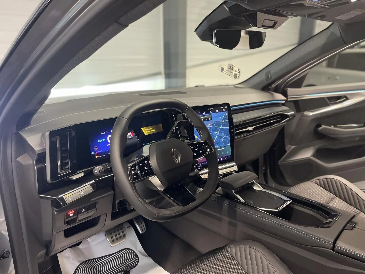 Intérieur avant droit du Renault Austral 2025 gris Schiste, volant multifonctions et grand écran tactile central visible.