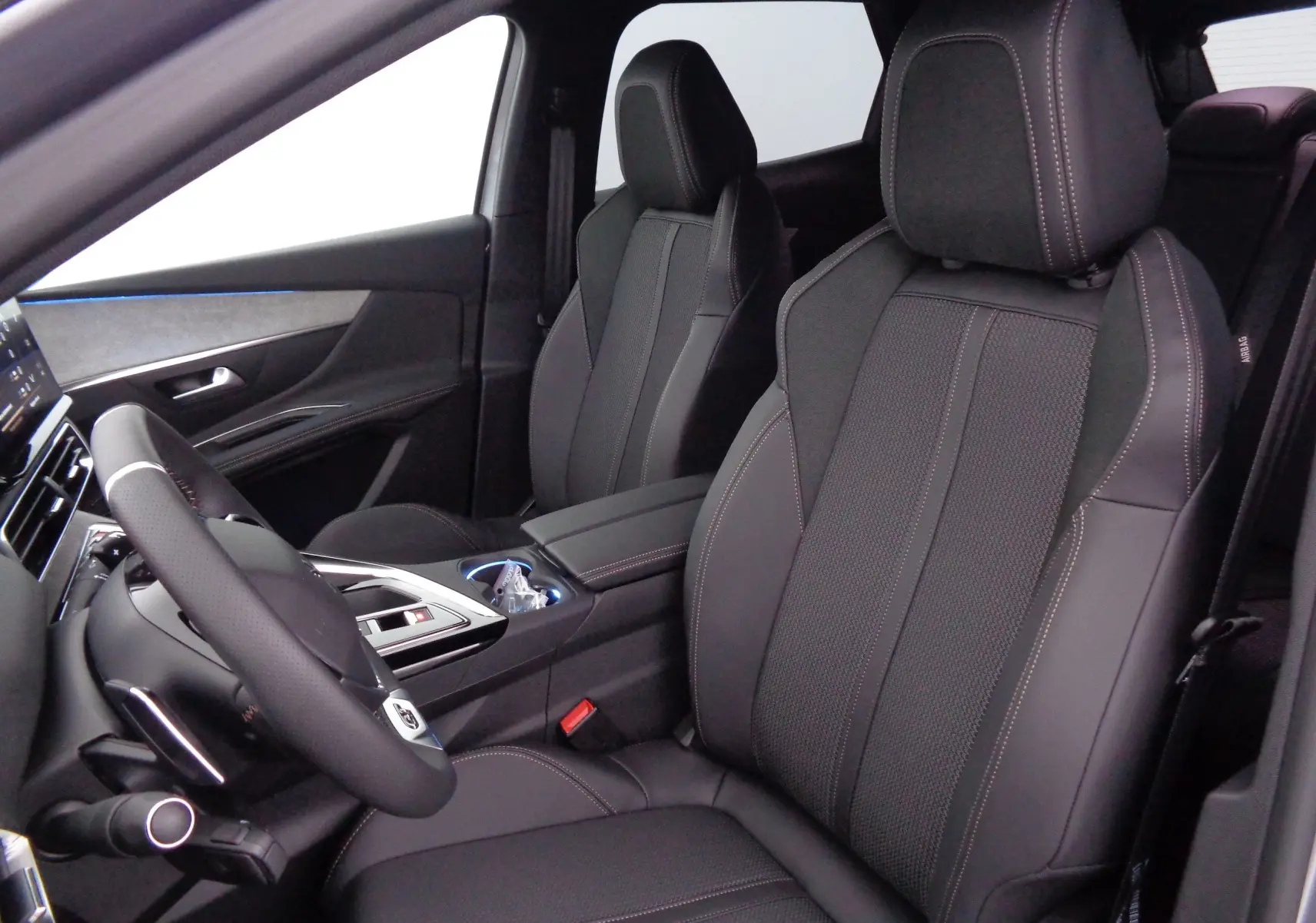 Vue intérieure côté conducteur du Peugeot 3008 2023, sièges en cuir noir avec surpiqûres contrastées.