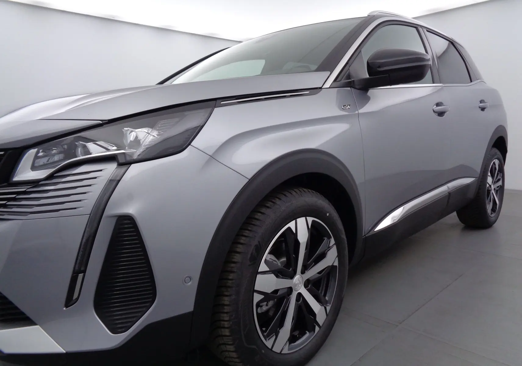 Peugeot 3008 gris Artense métal en vue 3/4 avant droit, avec jantes alliage et badge GT sur aile avant.