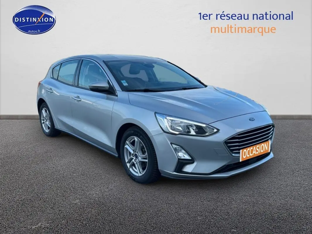 Ford Focus gris clair vue 3/4 avant droit avec jantes alliage et plaque "OCCASION" visible.