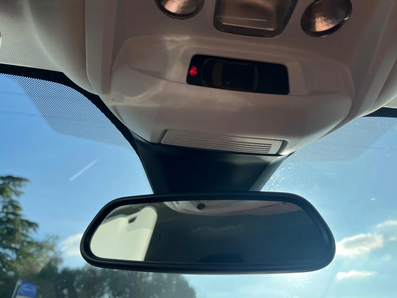Rétroviseur intérieur de Peugeot 3008 2023, vue centrée vers le pare-brise sous un ciel bleu lumineux.
