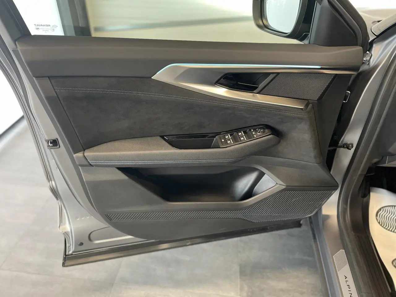 Porte avant gauche ouverte du Renault Austral gris satin mat, avec garniture noire et insert aluminium brossé.