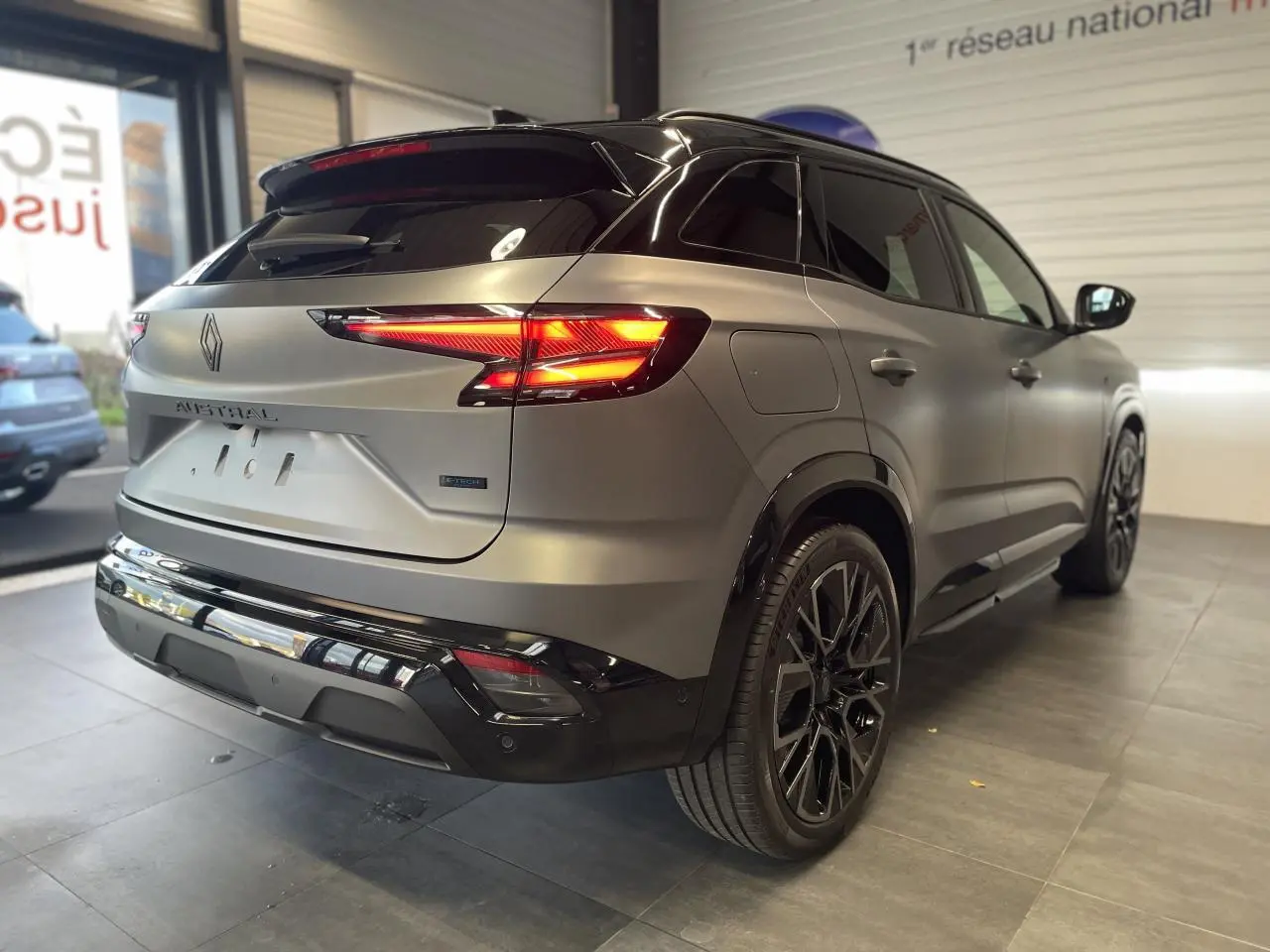 Vue 3/4 arrière droite du Renault Austral gris satin mat avec toit noir et jantes alliage noires en showroom.
