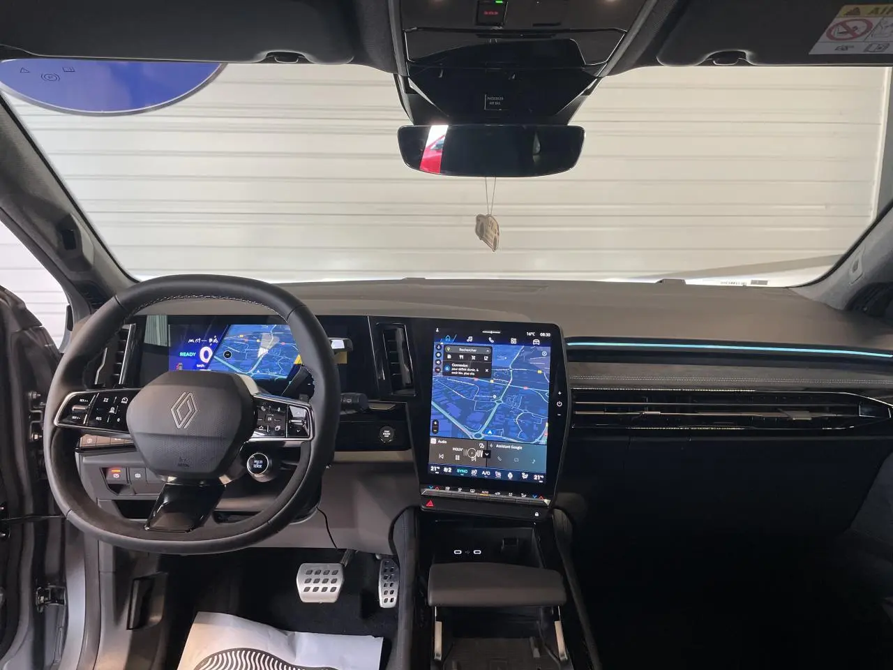 Vue intérieure avant du tableau de bord du Renault Austral gris satin mat avec écran tactile vertical et volant Alcantara.