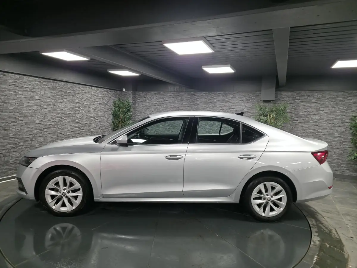 Profil côté gauche d'une Skoda Octavia gris métallisé 2023 dans un showroom avec jantes alliage 17 pouces.