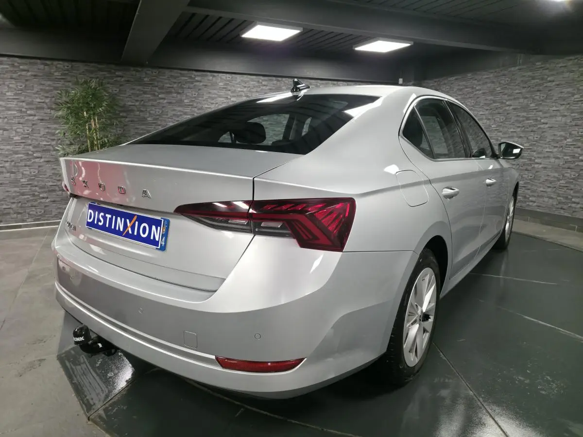 Vue 3/4 arrière droite d'une Skoda Octavia gris métallisé avec attelage fixe dans un showroom.