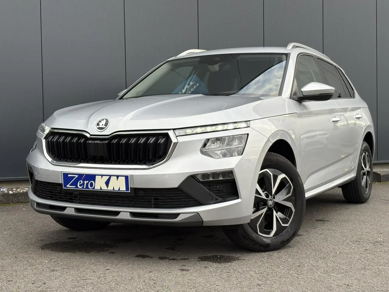 Vue 3/4 avant droite d'un Skoda Kamiq gris argent avec calandre noire et jantes alliage bicolores.