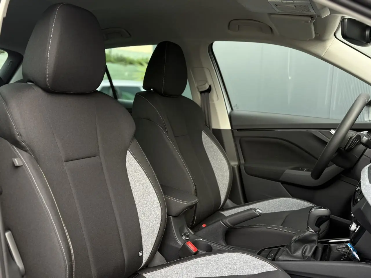 Vue intérieure côté droit montrant les sièges bicolores noirs et gris du Skoda Kamiq 2025 avec accoudoir central.