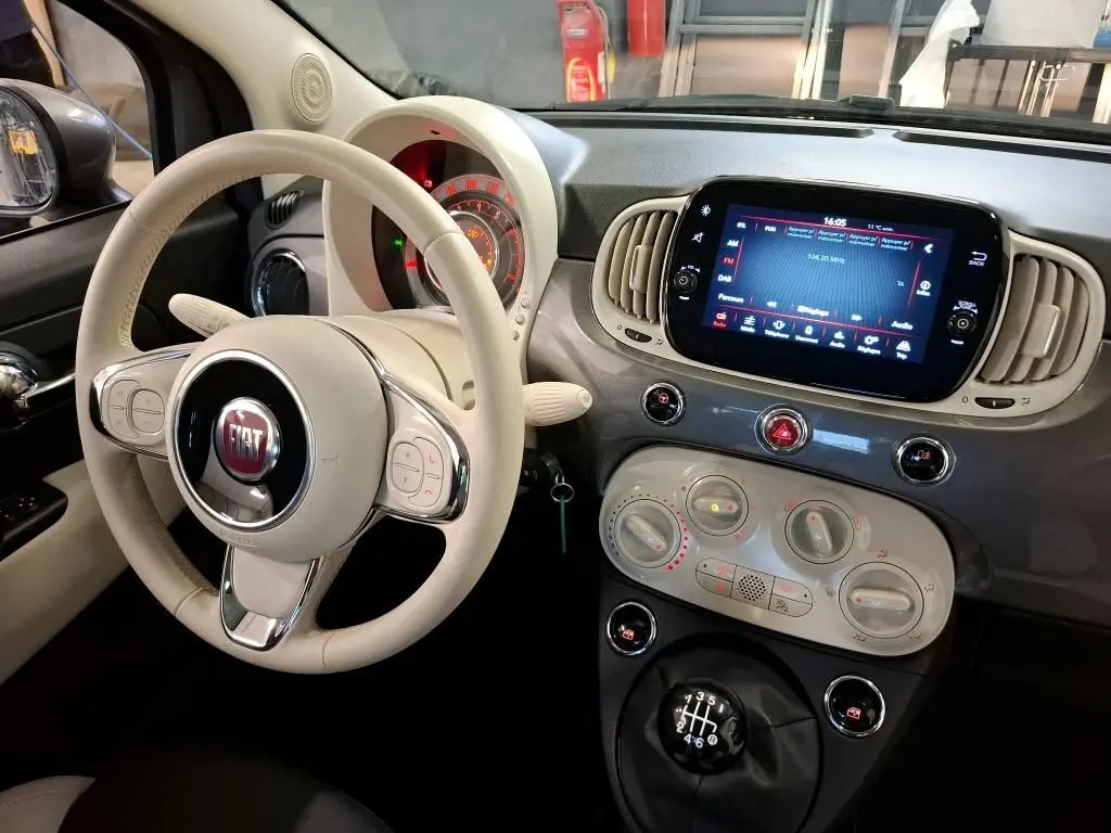 Vue intérieure côté conducteur de la Fiat 500 2022 Gris Electroclash, volant beige et tableau de bord avec écran tactile.