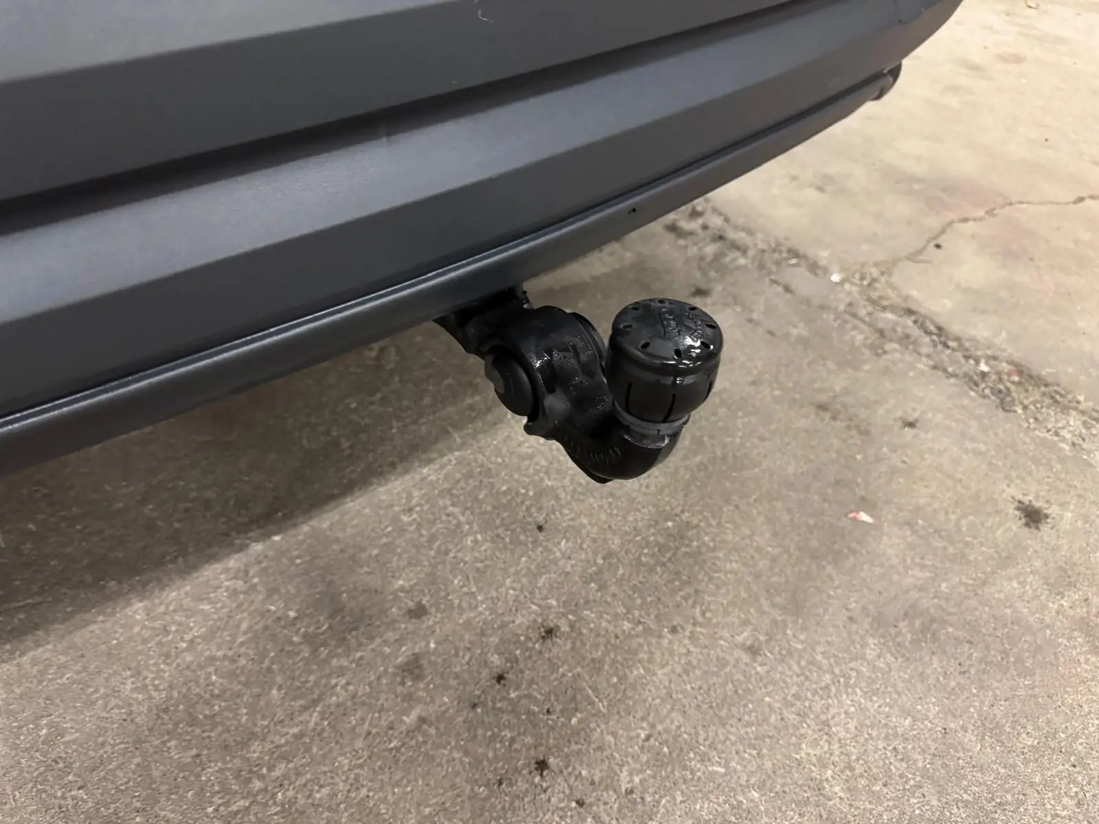 Gros plan sur l'attelage d'une Audi Q3 Business gris, visible sous le pare-chocs arrière dans un garage.