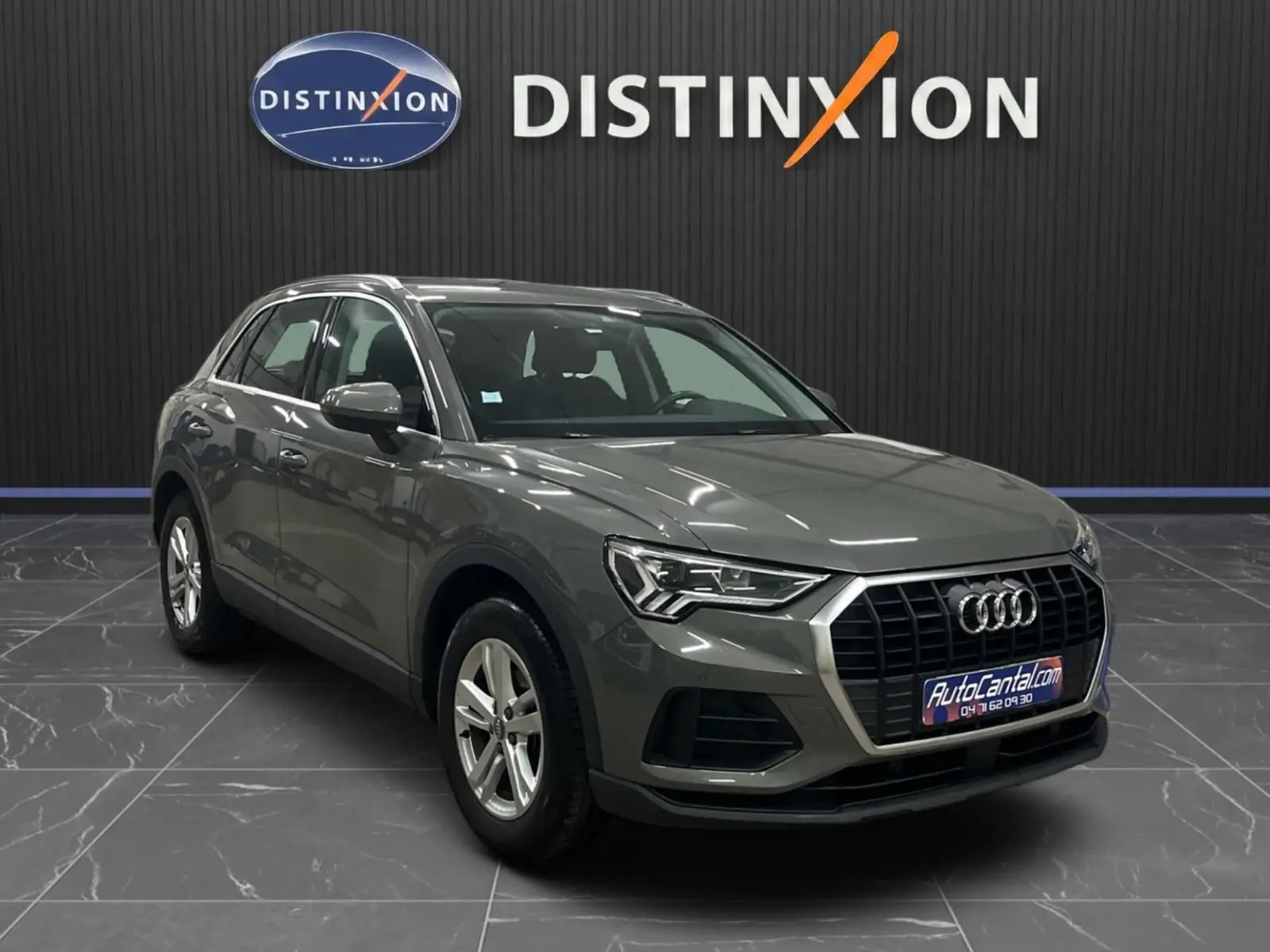Audi Q3 Business gris en 3/4 avant droit, mettant en valeur la calandre hexagonale et les phares LED distinctifs.