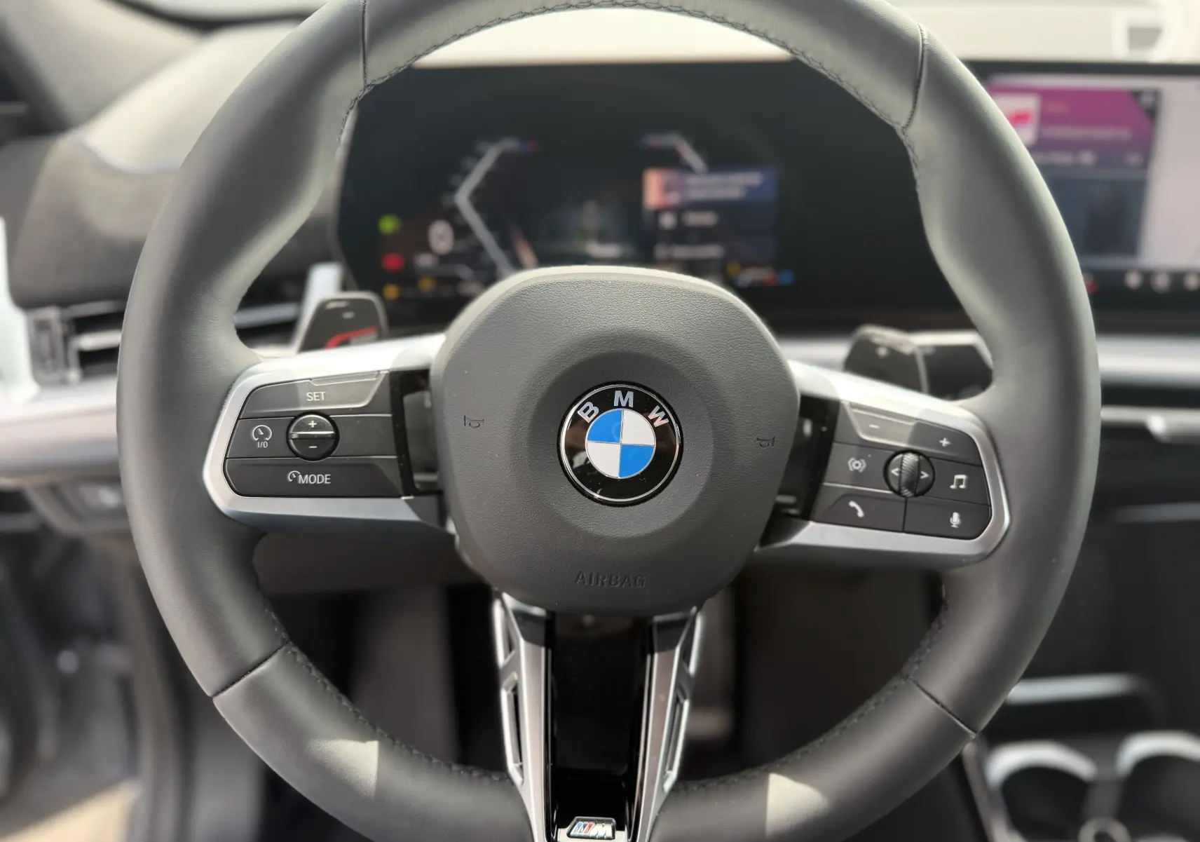 Gros plan sur le volant cuir noir avec logo BMW et commandes intégrées du BMW X2 2025, intérieur moderne et épuré.