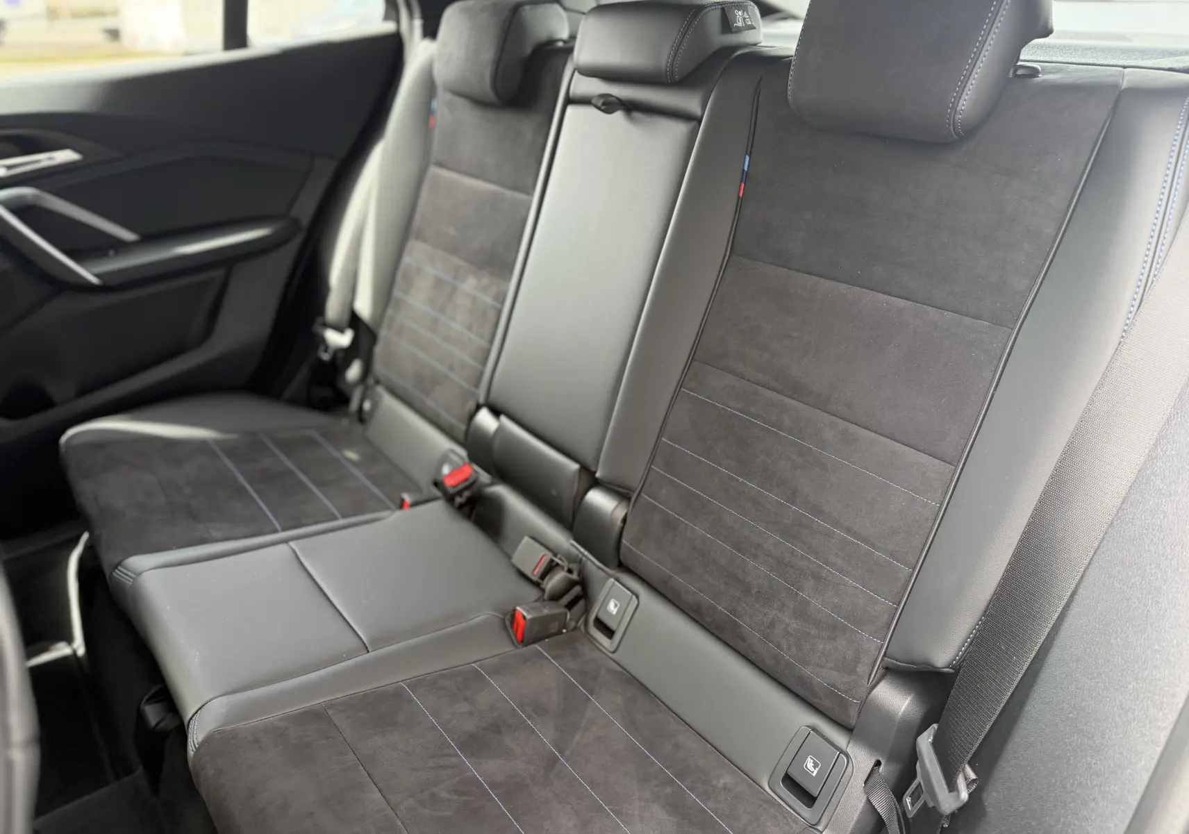 Vue intérieure des sièges arrière en cuir et alcantara noirs avec surpiqûres bleues d'une BMW X2 2025 Skyscraper.