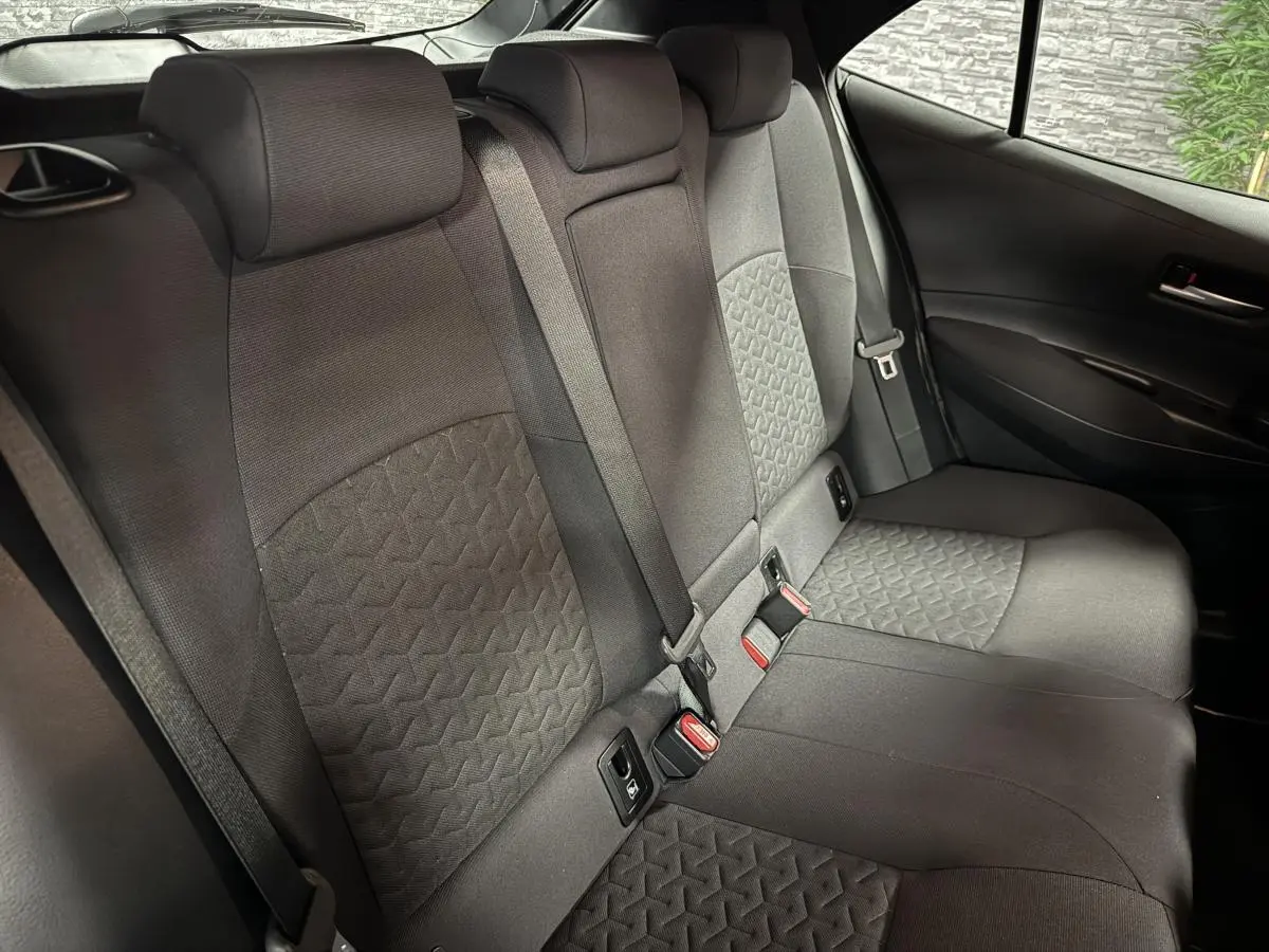 Vue intérieure de la banquette arrière en tissu noir de la Toyota Corolla hybride 2022, avec ceintures et fixations ISOFIX visibles.