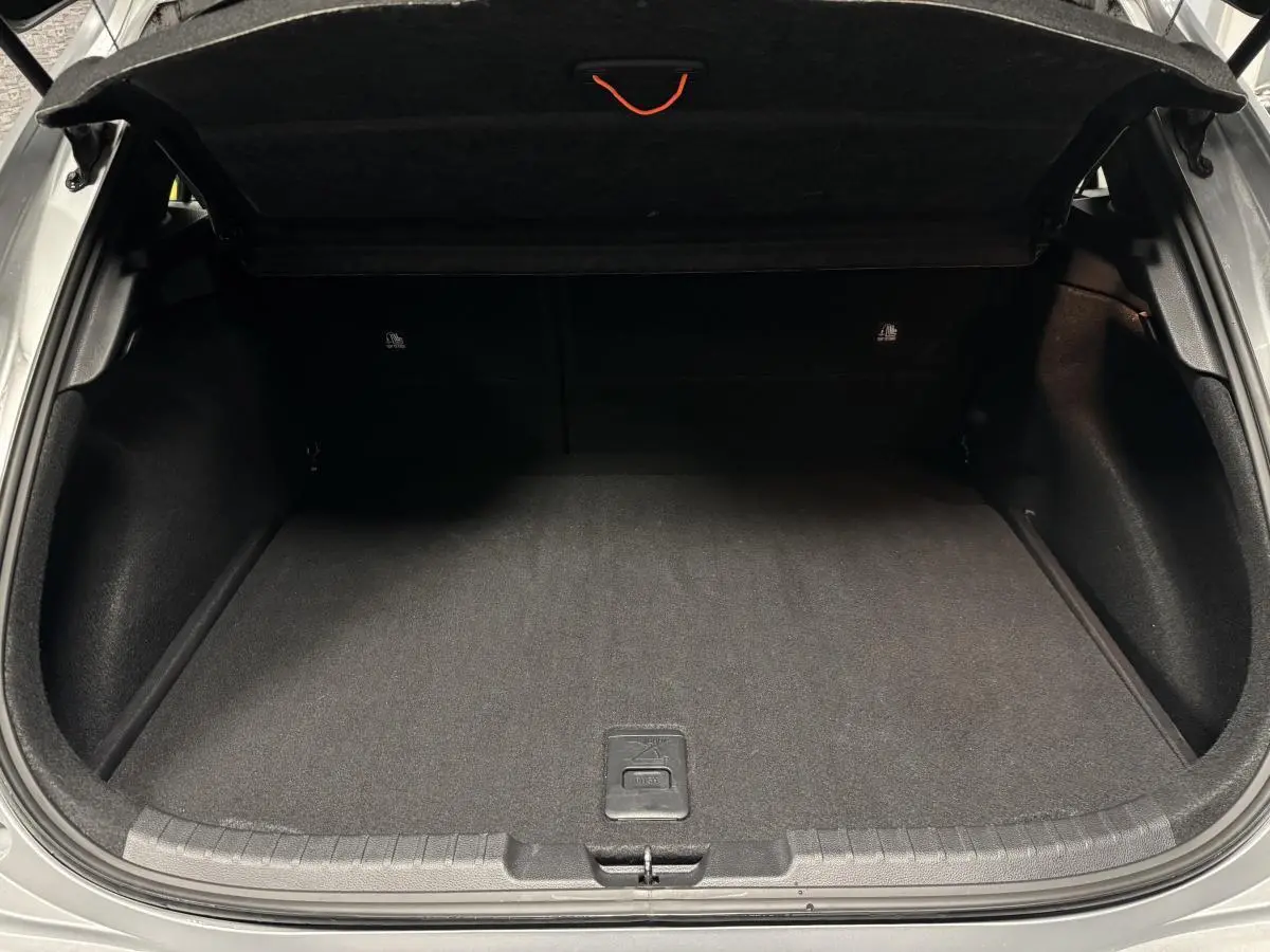 Coffre ouvert d'une Toyota Corolla hybride gris, montrant un espace de rangement propre et bien fini.