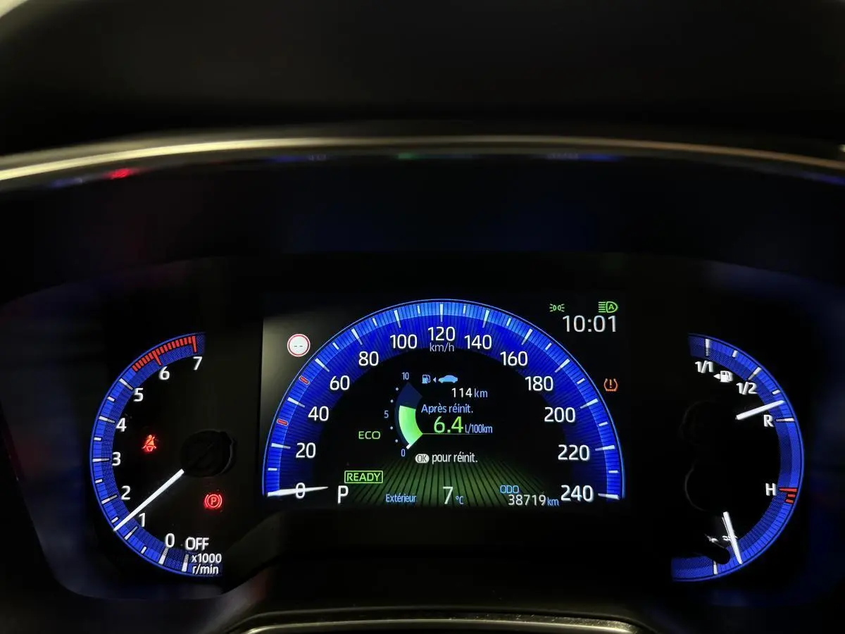 Tableau de bord numérique de Toyota Corolla hybride 2022 avec affichage bleu, consommation et vitesse en km/h.