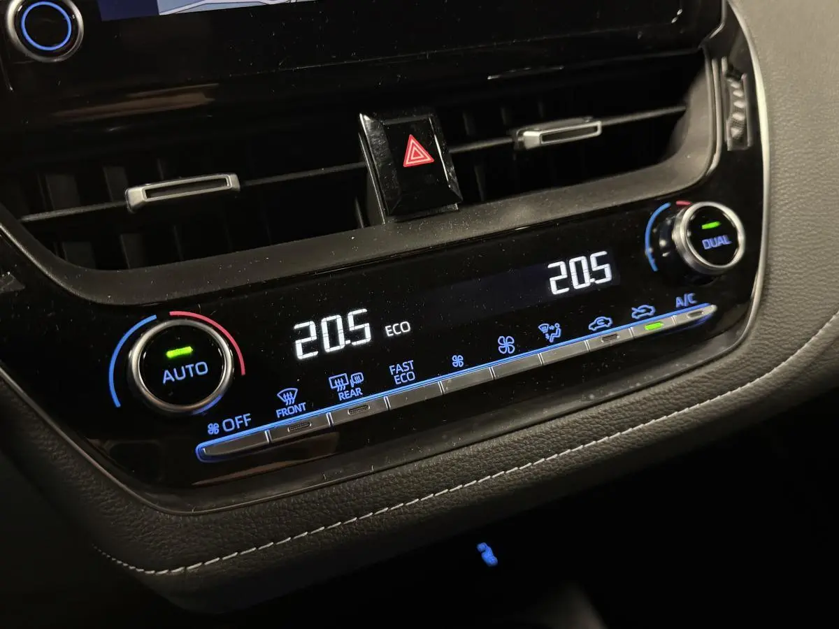 Détail de la console centrale noire laquée avec climatisation automatique bi-zone de la Toyota Corolla hybride gris 2022
