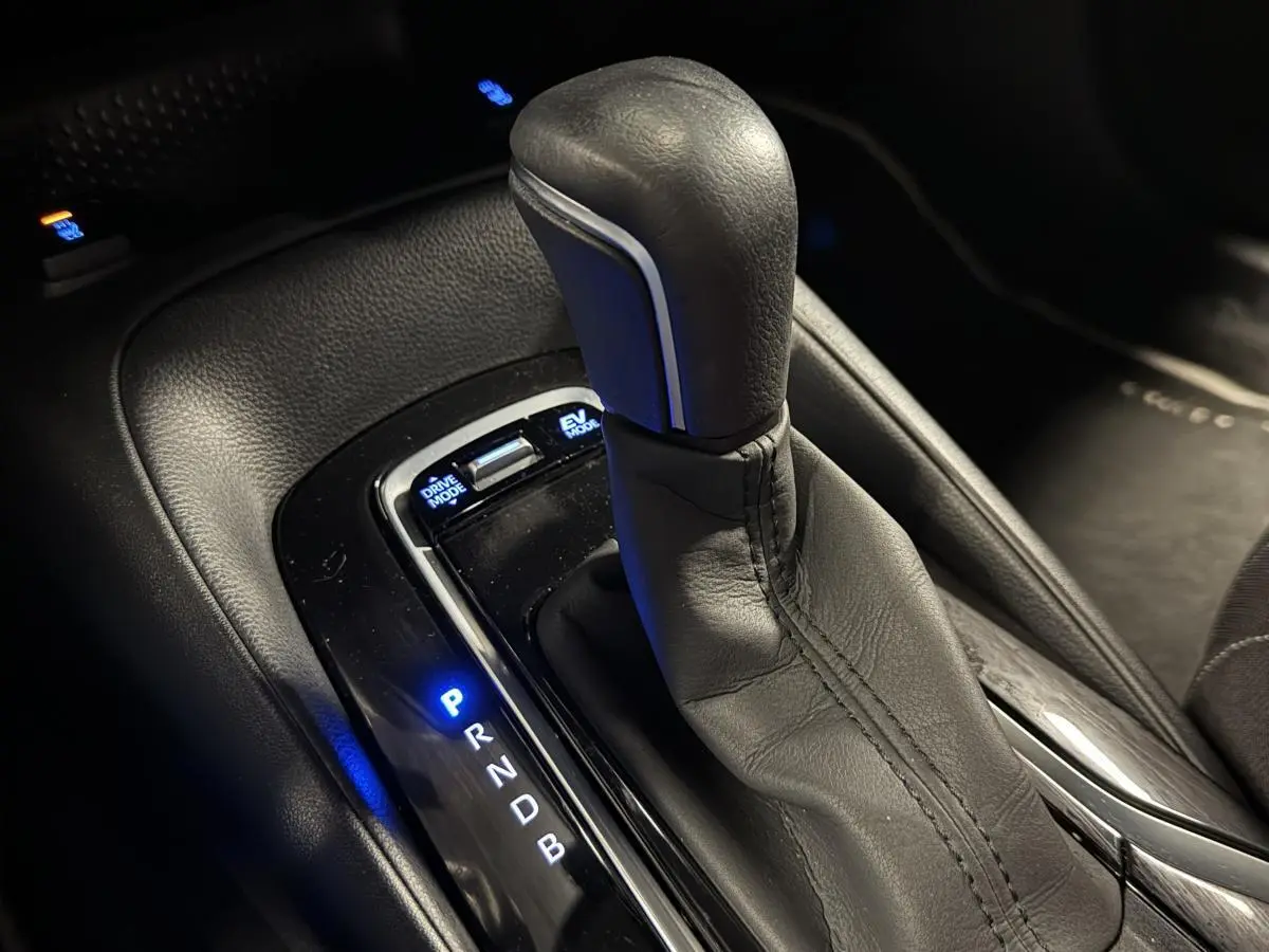 Le levier de vitesses en cuir noir de la Toyota Corolla hybride 2022 avec éclairage bleu des modes de conduite.