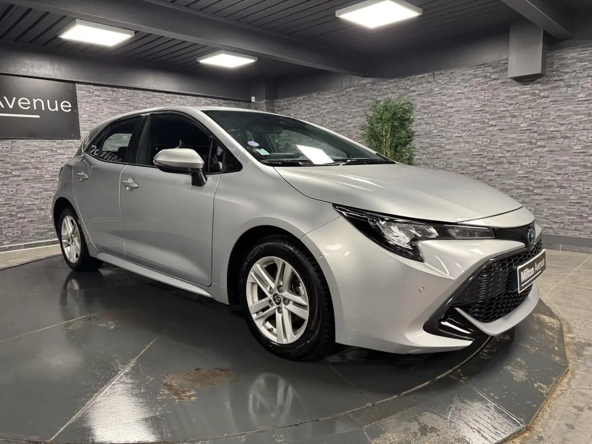 Toyota Corolla hybride gris métallisé vue 3/4 avant droit avec calandre noire et jantes alliage 16 pouces