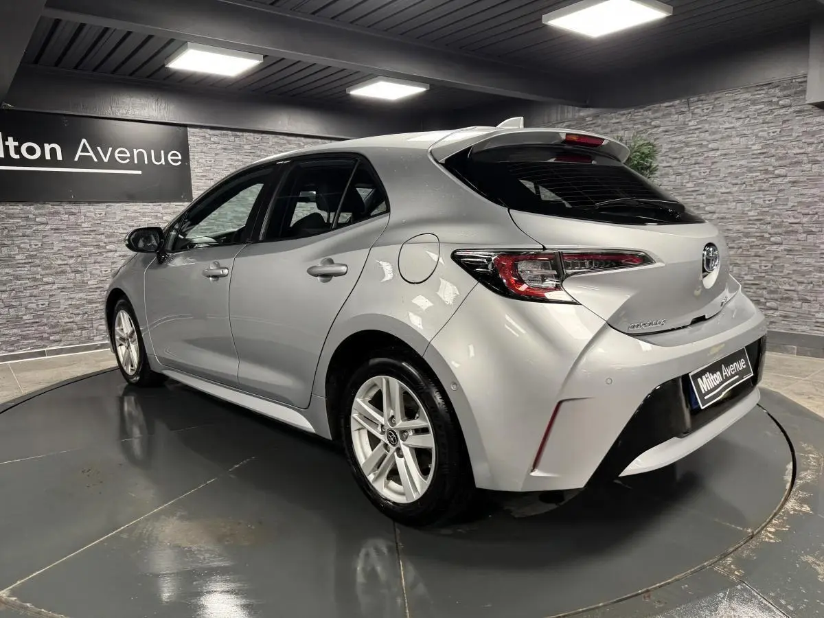 Vue 3/4 arrière droite d'une Toyota Corolla hybride 2022 gris métallisé avec jantes alliage et feux LED distinctifs.
