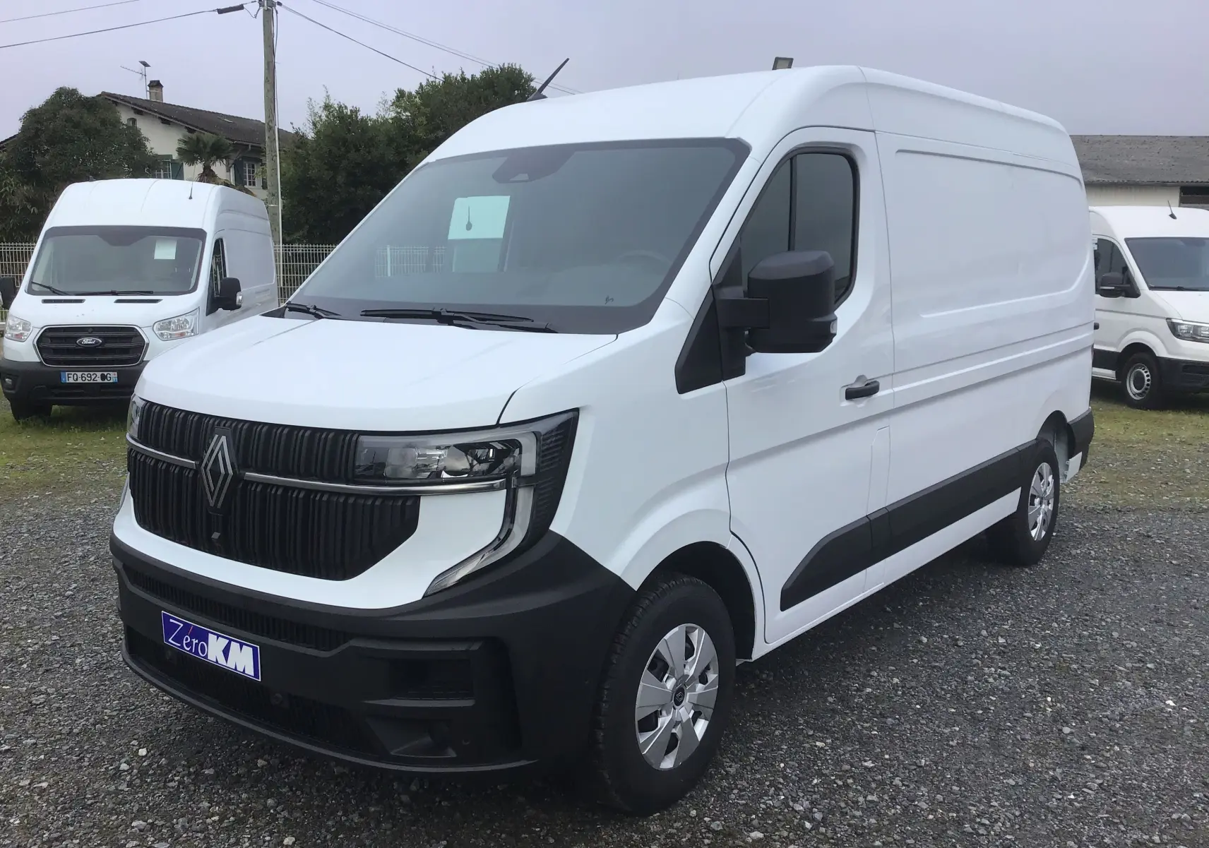 Vue 3/4 avant droit d’un utilitaire Renault Master blanc avec calandre noire et jantes argentées sur parking extérieur.