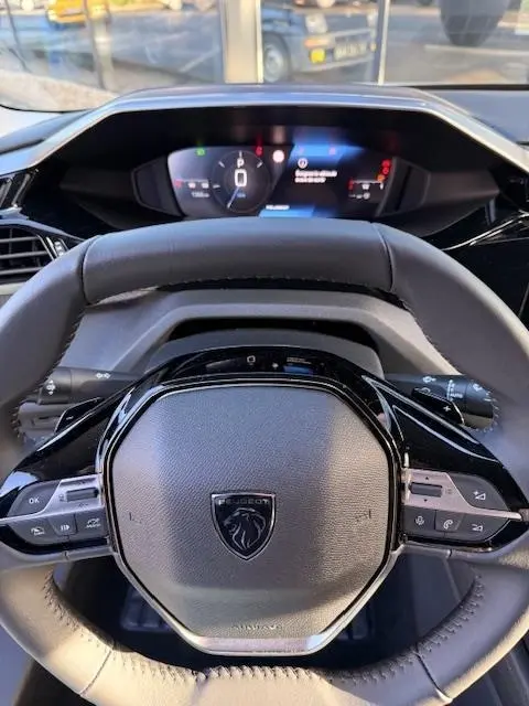 Vue intérieure centrée sur le volant cuir noir et le combiné d'instruments numérique de la Peugeot 308 Hybrid 145 e-DCS6 Allure.