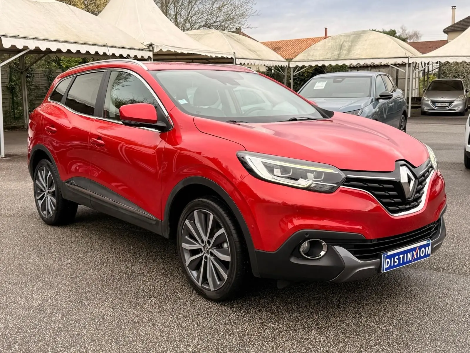 Renault Kadjar rouge flamme en 3/4 avant droit, mettant en valeur ses jantes bi-ton et ses optiques modernes.