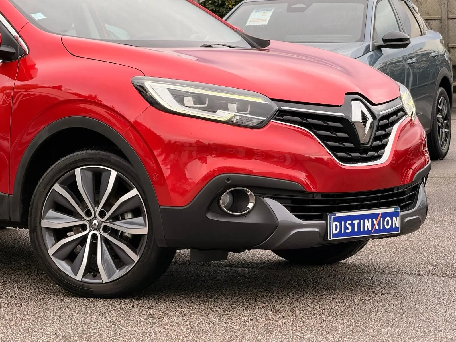 Vue 3/4 avant gauche d'un Renault Kadjar rouge flamme avec calandre noire et jantes alliage bi-ton.