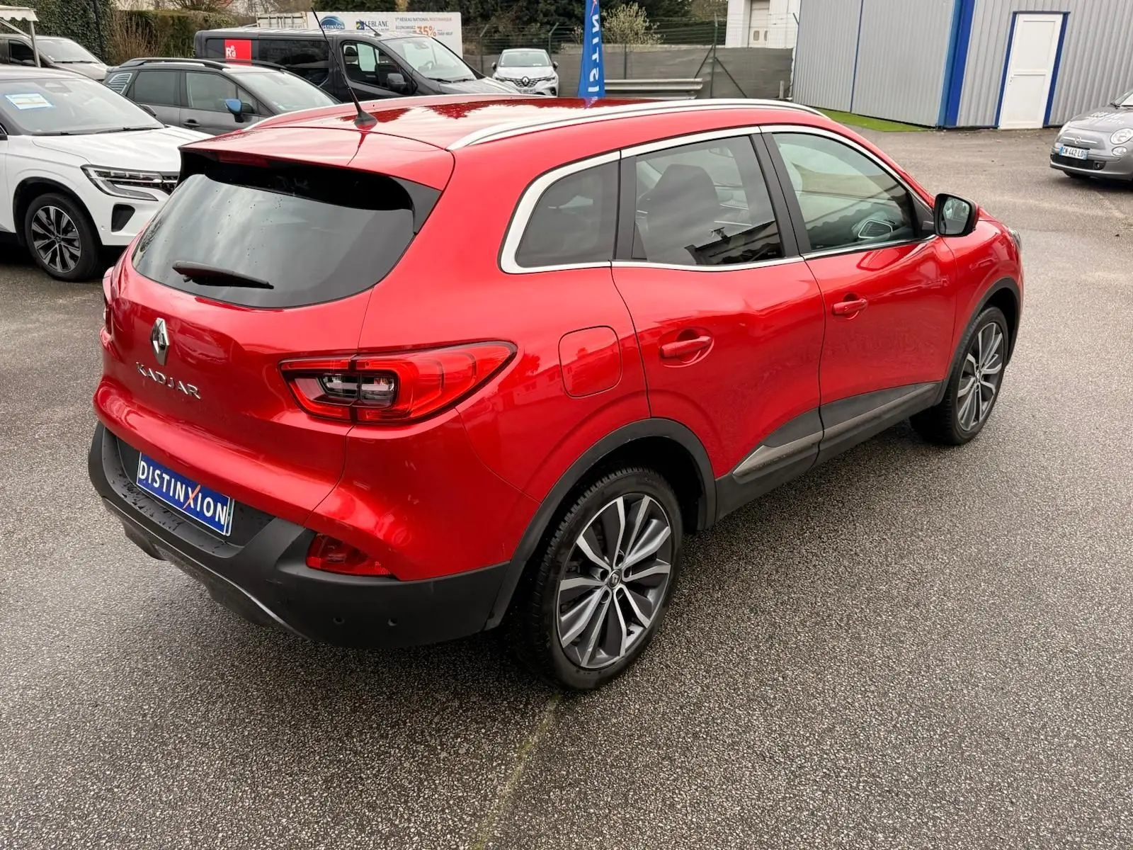Vue 3/4 arrière droite d'un Renault Kadjar rouge flamme avec jantes alliage bi-ton et vitres teintées.