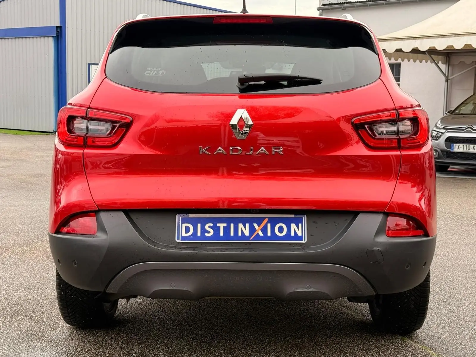 Vue arrière d'un Renault Kadjar rouge flamme de 2016 avec pare-chocs noir et plaque d'immatriculation Distinxion.