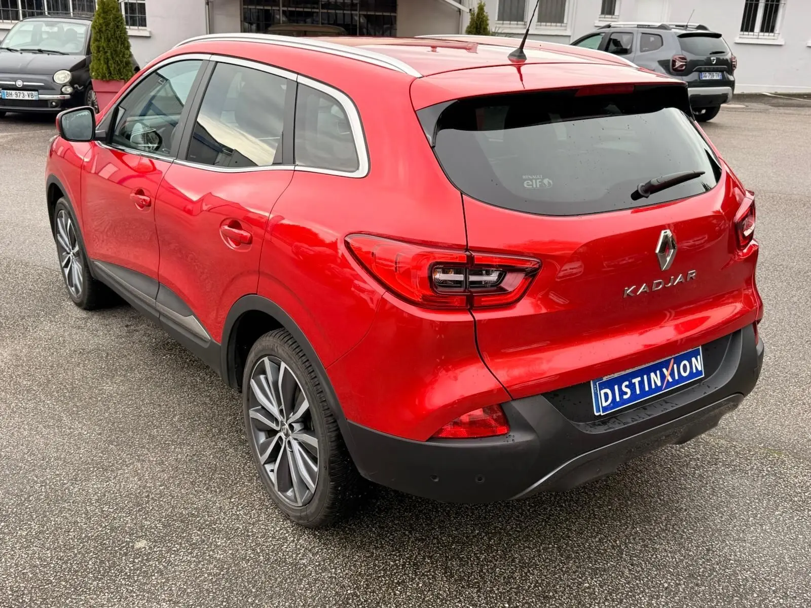 Vue 3/4 arrière droite d’un Renault Kadjar rouge flamme avec jantes alliage bicolores et toit panoramique.
